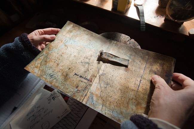 from above, a map with pin holes shining in the light is held in hand