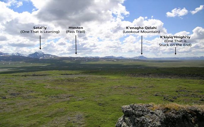 tree-less green plain leading up to mountains, with four points called out in text.  from left to right, one that is leaning, pass trail, lookout mountain, one that is stuck on the end