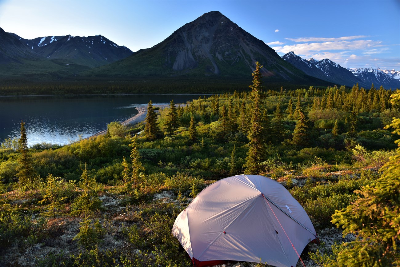 a tent in the setting sun along the shore of a lake
