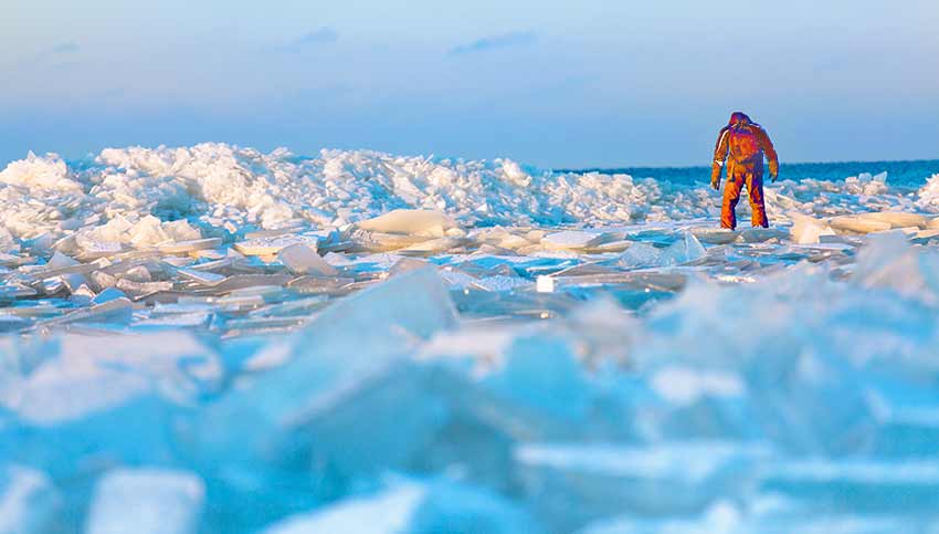 A researcher walks along an icy beach