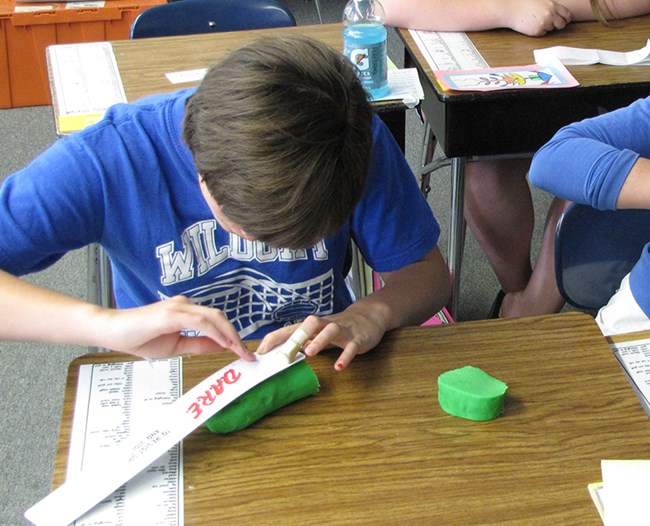 A student uses play dough to make scale models of planets.