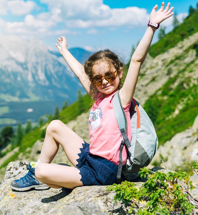 A child sitting on a rock on a mountainside.