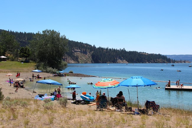 Families with children play on the beach and in the water on a sunny day