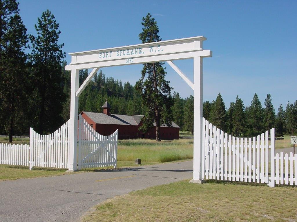 Color photo of Fort Spokane entrance gate with mule barn in the background