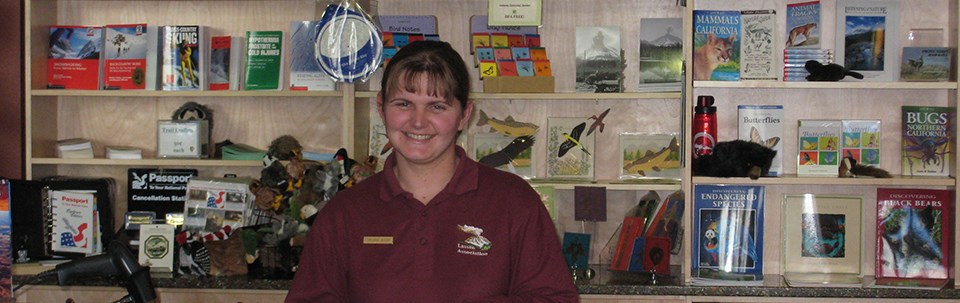 A women in a red shirt stands at a counter in a gift store