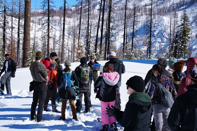 a ranger talks to a group of kids on a snow-covered hill in winter