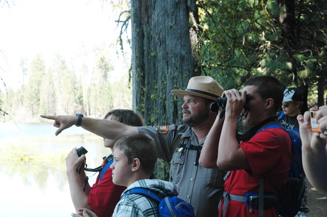 ranger pointing out of frame, drawing the eye of school children around him