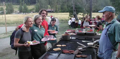 Ed hosts the modern wednesday night bbq.  He is talking to visitors in front of the food