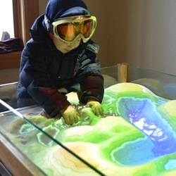 A boy plays with an augment reality sandbox
