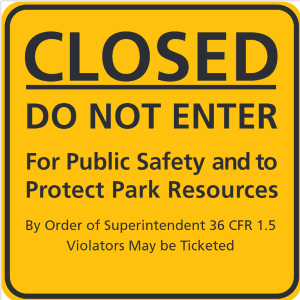 A square yellow sign that reads "Closed. Do Not Enter. For Public Safety and to Protect Park Resources. By Order of Superintendent 36 CFR 1.5. Violators May Be Ticketed.