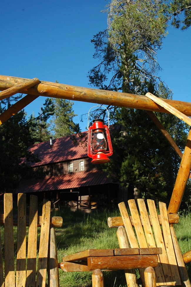 red antique lantern and adirondak chairs with historic ranch building behind