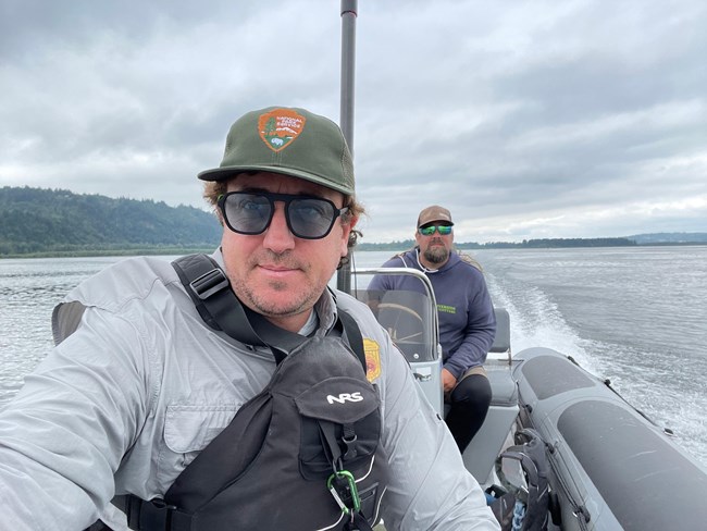 a man in a park ranger uniform and life jacket motorboats through a large body of water