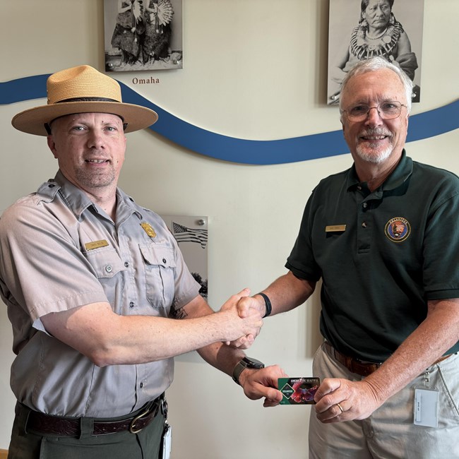 two men in park service attire shake hands