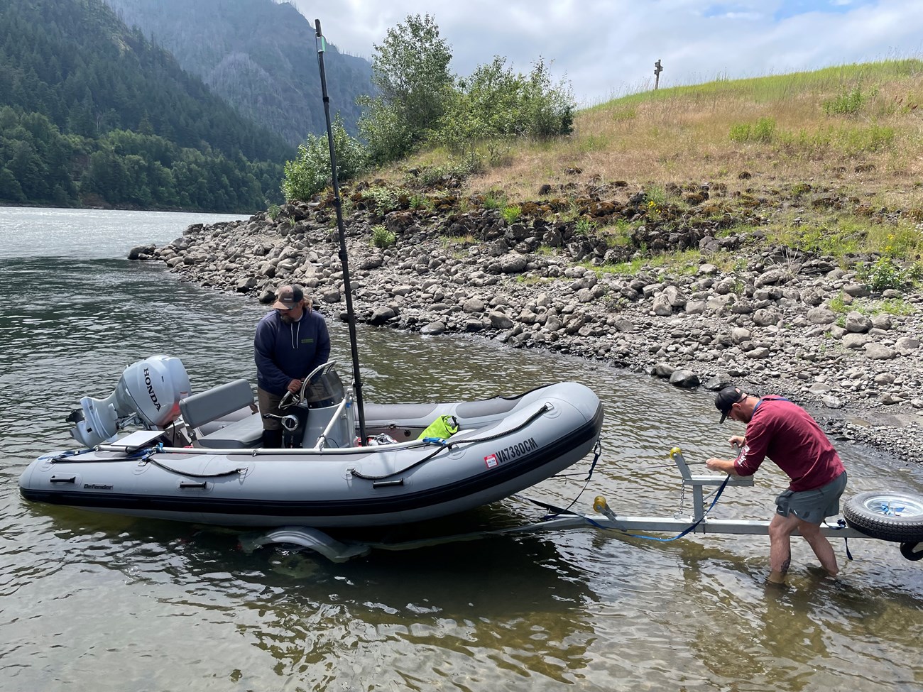 two men loading a boat on the banks of a river