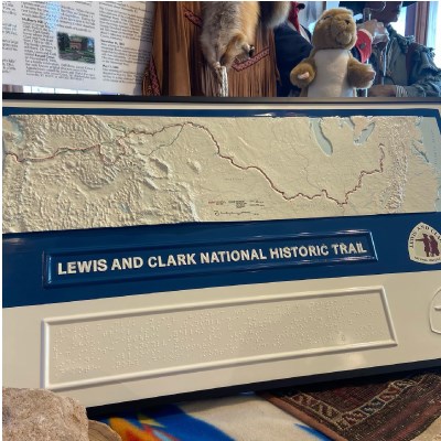 Tactile map of Lewis and Clark Trail propped up on visitor center table. The map is 3D relief, with braille.