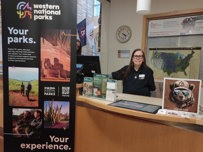 a woman stands behind a desk and signs