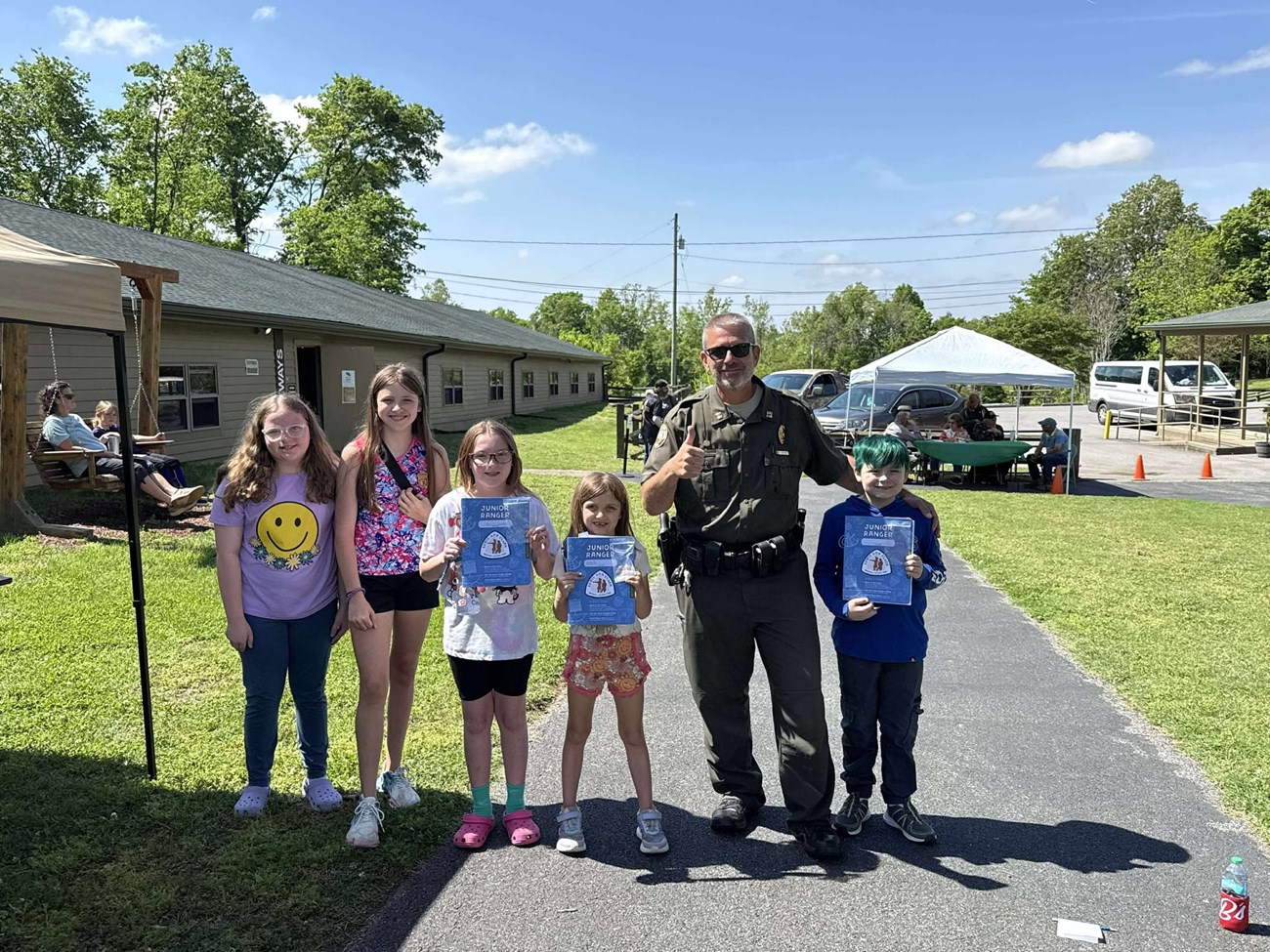 five children stand near a man in a law enforcement ranger uniform