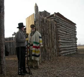 Reenactors stand outside of replica of Camp Dubois, a log fort.