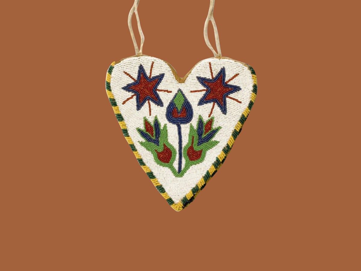 White beaded bag on orange background. Beadwork by Nez Perce artist with two flowers and stars in blue, red, and green