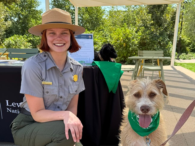 A woman in a park ranger uniform and a dog in a bandana