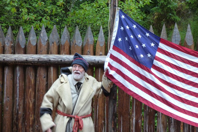 A ranger wearing period clothing holding a 15 star and stripe flag
