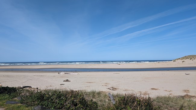 A view of the ocean over a flat sandy beach