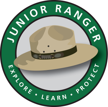 Cartoon ranger hat in a green circle with words around: Junior Ranger Explore Learn Protect
