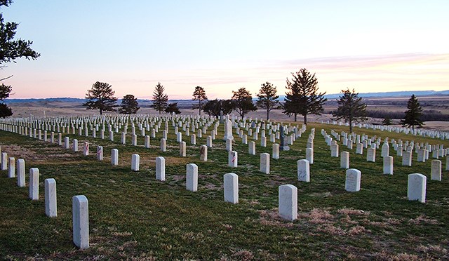 Photo of the Custer National Cemetery at sunset.  View is to the southwest and many rows of white headstones.
