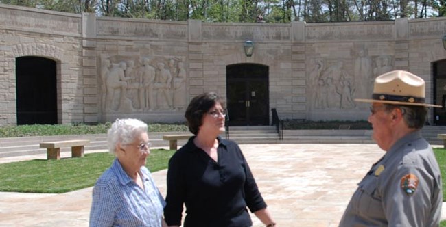 Park Ranger talking with two older women in front of limestone block building