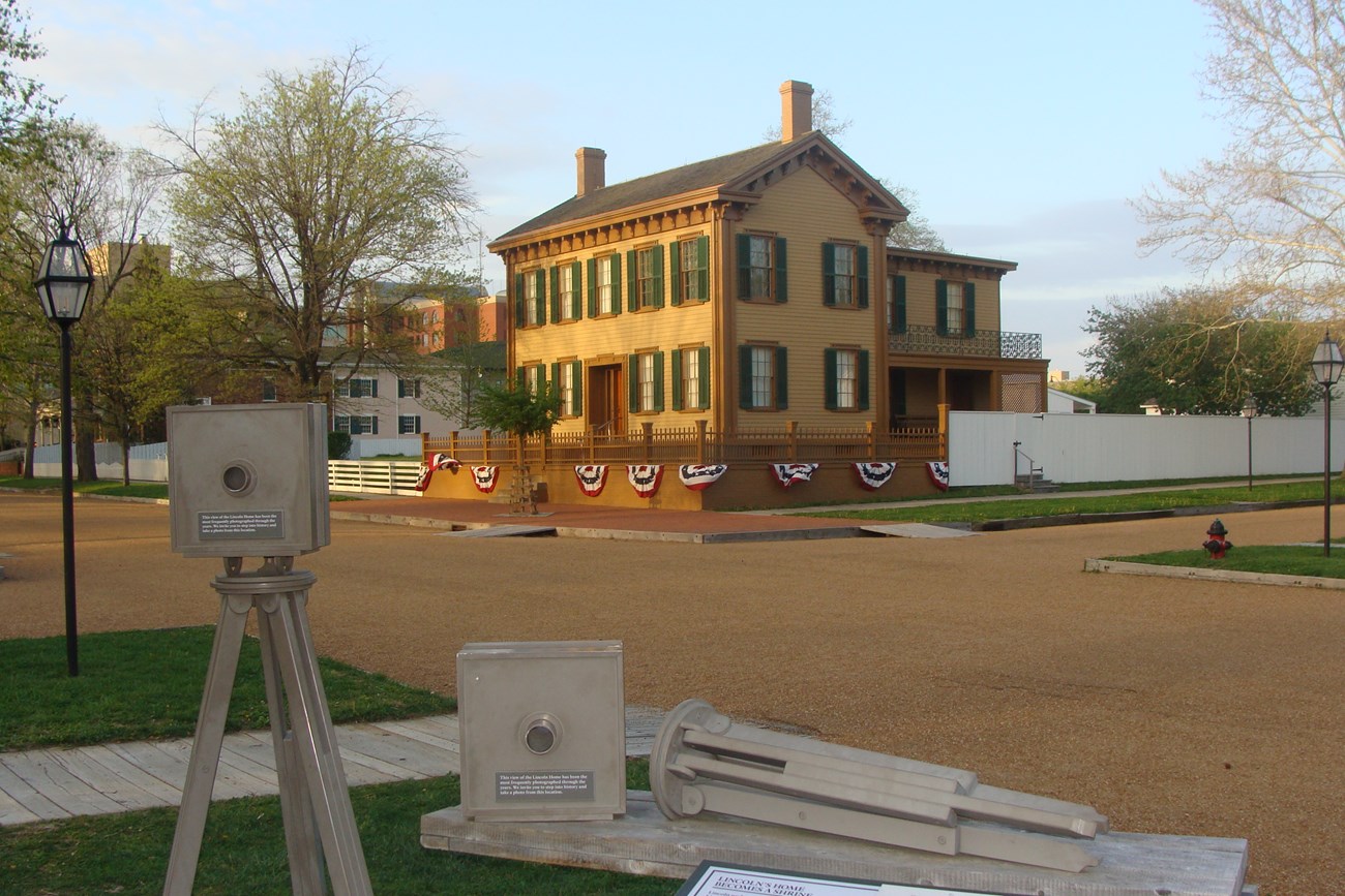 Lincoln Home - a two-story tan house with green shutters in the distance