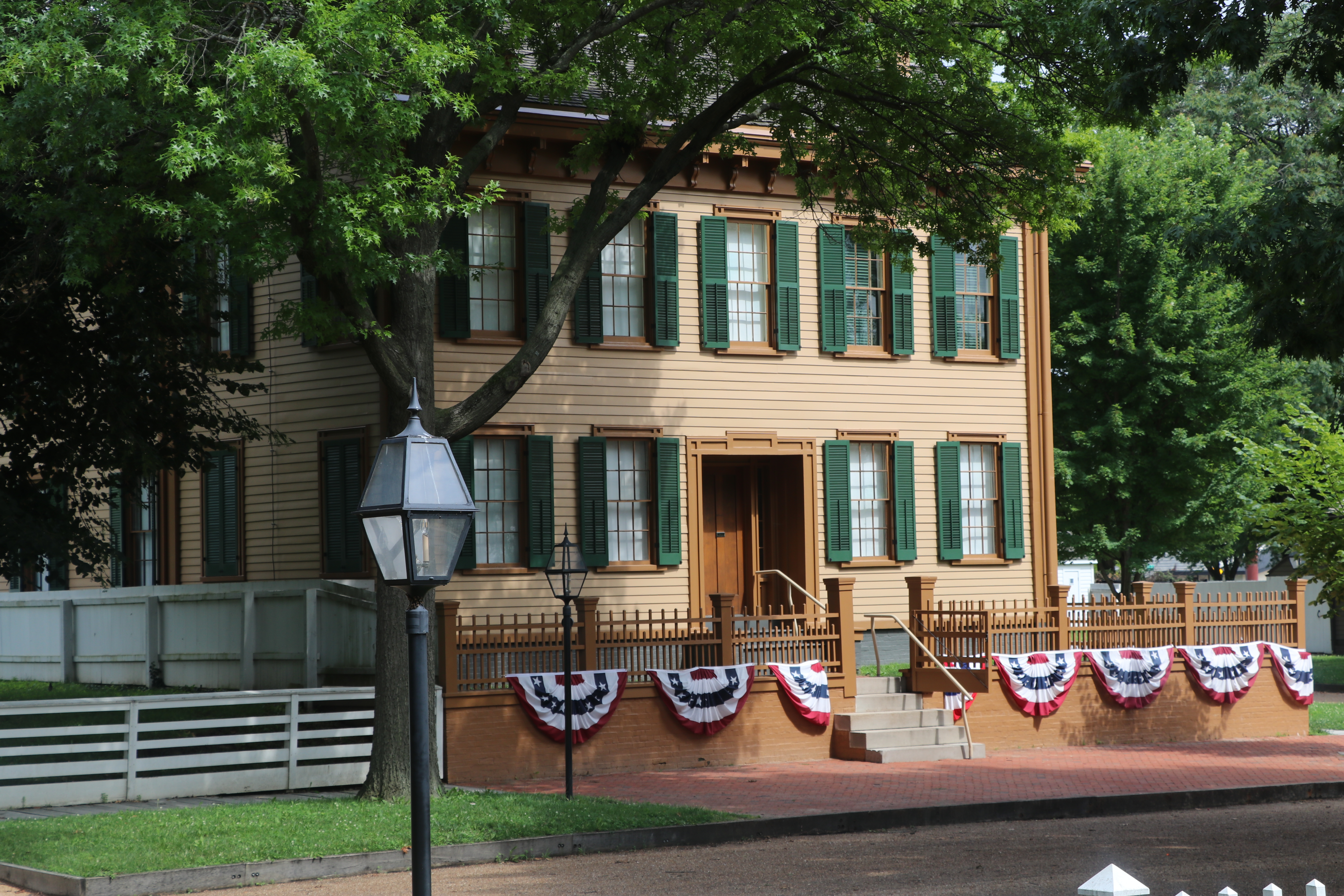 The two-story Lincoln Home with patriotic bunting along the fence in front of the home.