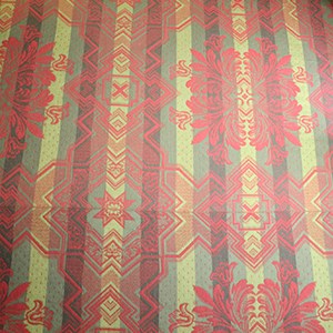 Carpet of stripes of dark and light green with red geometric shapes and flowery crest shape pattern overlaid on stripes