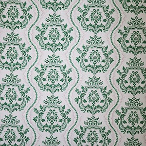 white wallpaper with repeating vertical pattern of emerald green intricate crests embellished with leaves