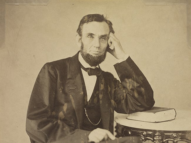 Bearded president Lincoln leaning with arm on table