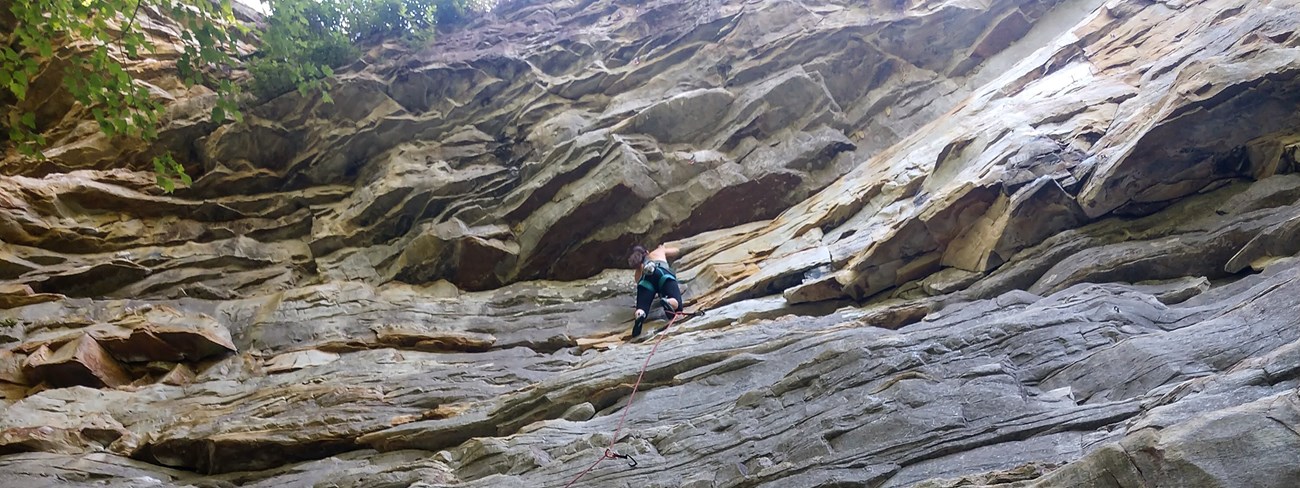 Woman climbing high up on a sandstone wall