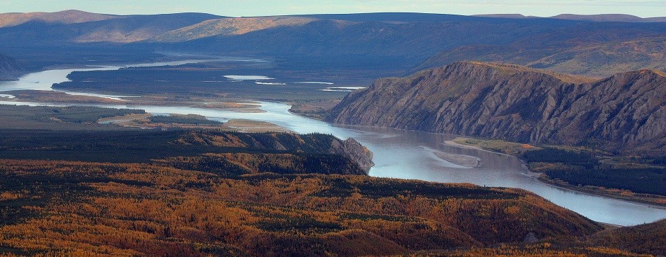 a rive winds through mountains covered in orange vegetation