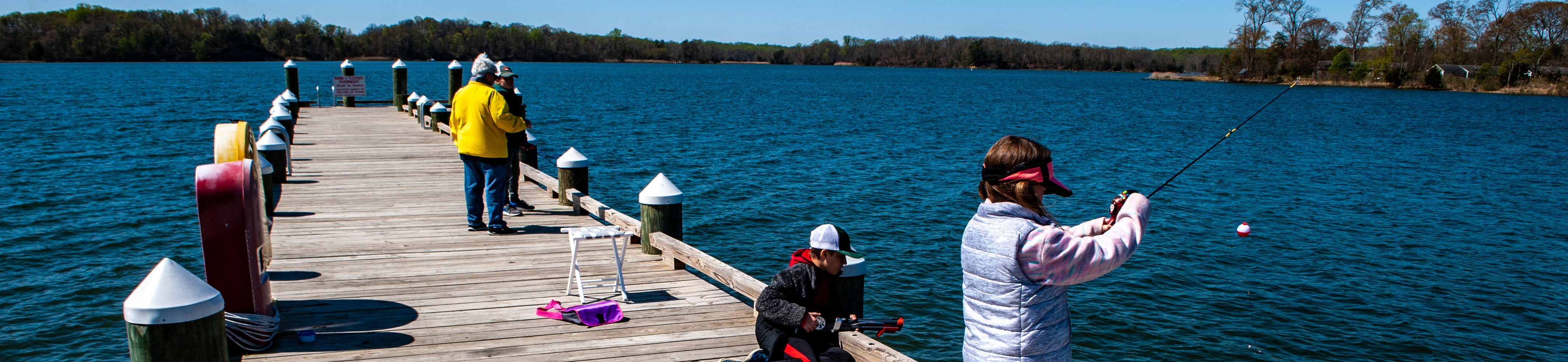 Several people fish from a pier.