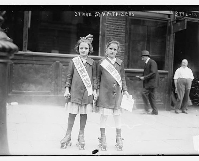 Black and white photo of two young girls wearing sashes