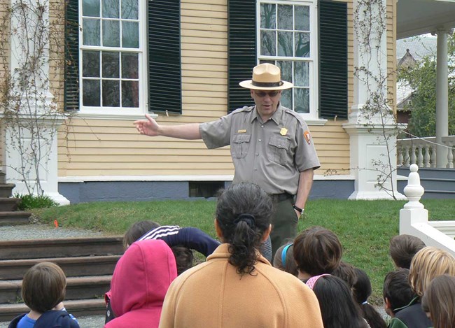 Ranger talking to group of children in front of Longfellow House