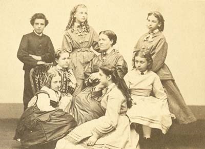 Group portrait of woman seated with six girls and one boy seated and standing around her