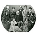 a black and white historical family photo with 10 family members wearing period clothes from the 1800s.
