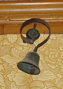 Bell hanging on curved metal bracket
