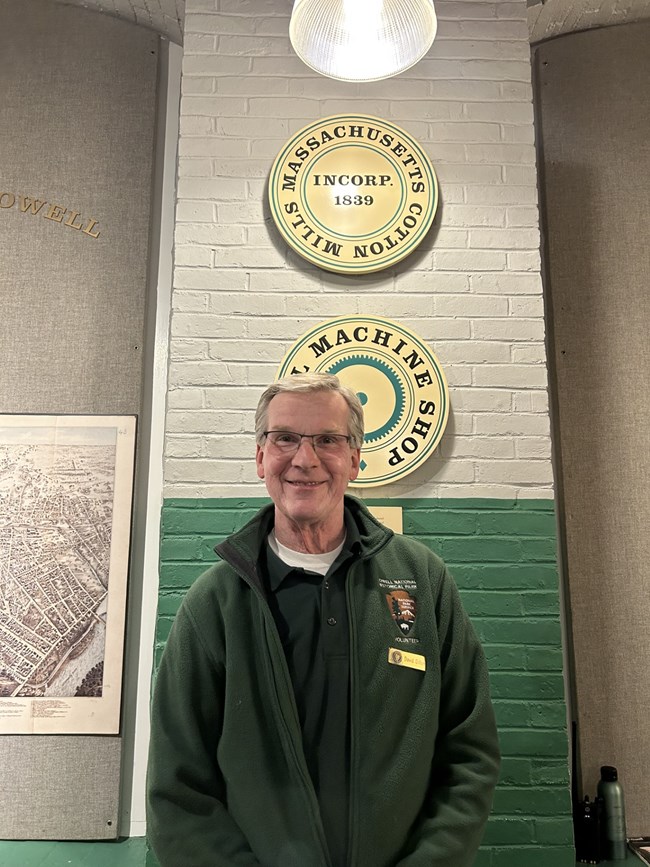 Volunteer for National Park Service standing in front of green and white wall in the Boott Cotton Mills Museum