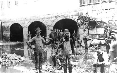 A historic image of a group of canal workers posing with their tools in the Merrimack Canal