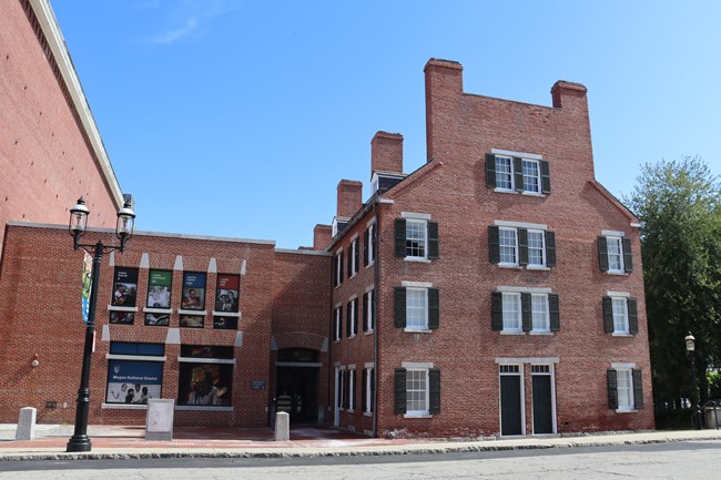 A four story brick building with many windows.  In the middle is an entrance door.