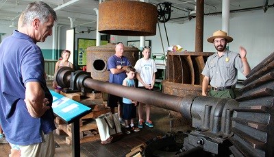 A park ranger explains a large machine to a group of visitors