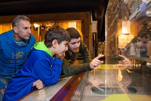 A park ranger helps a father and son explore a model of the factory