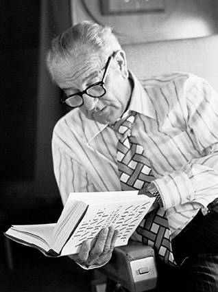 Lyndon Johnson wears glasses as he reads from an open book.