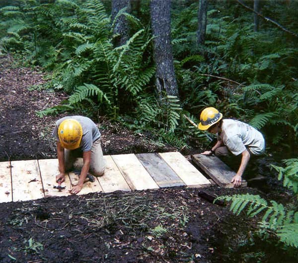 Two volunteers repairing a footbridge in the park