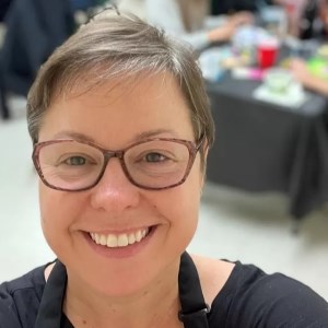 selfie of woman smiling at camera with artists working at tables in background